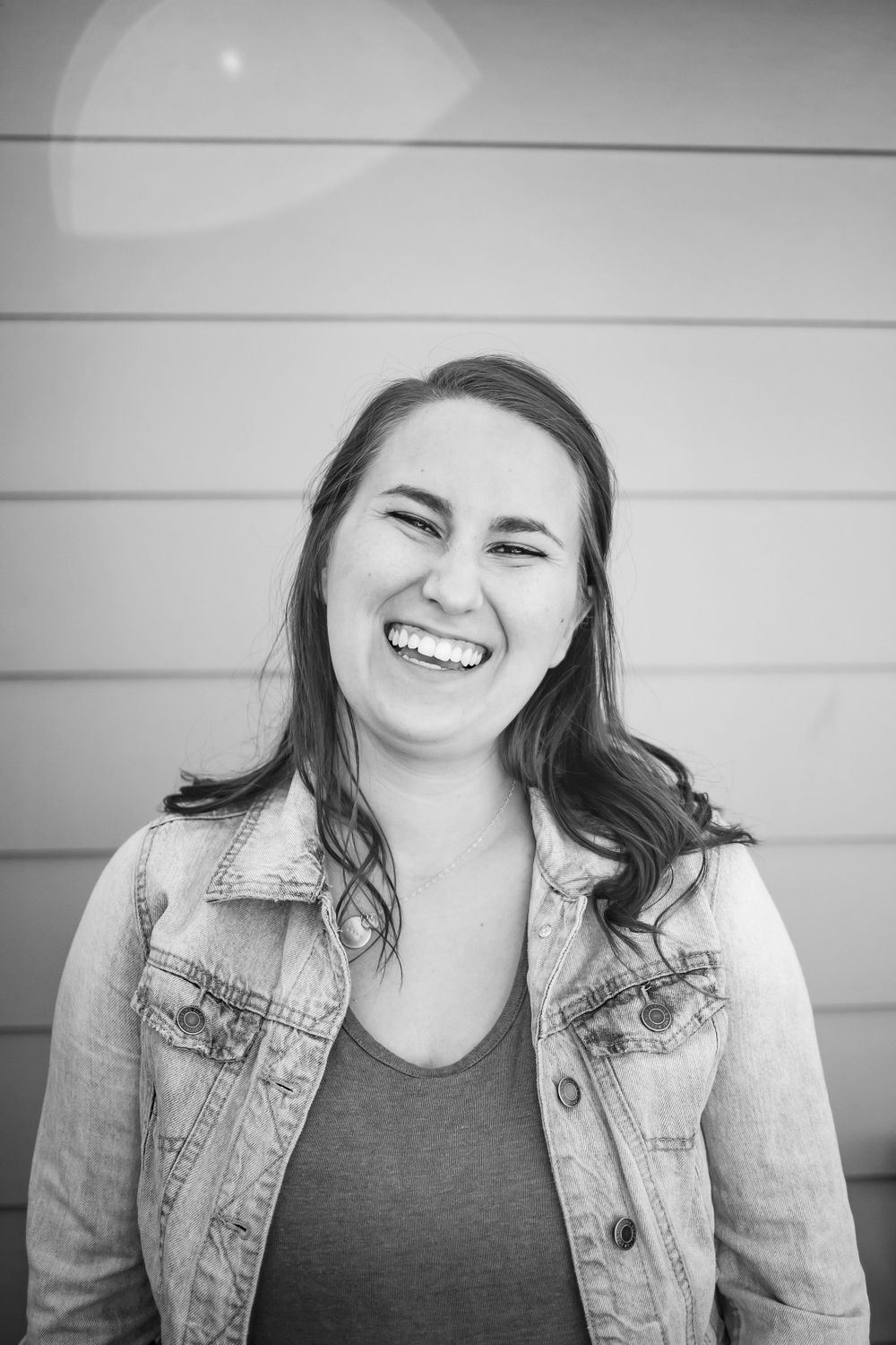 Black and white portrait with joyful expression against wooden wall.