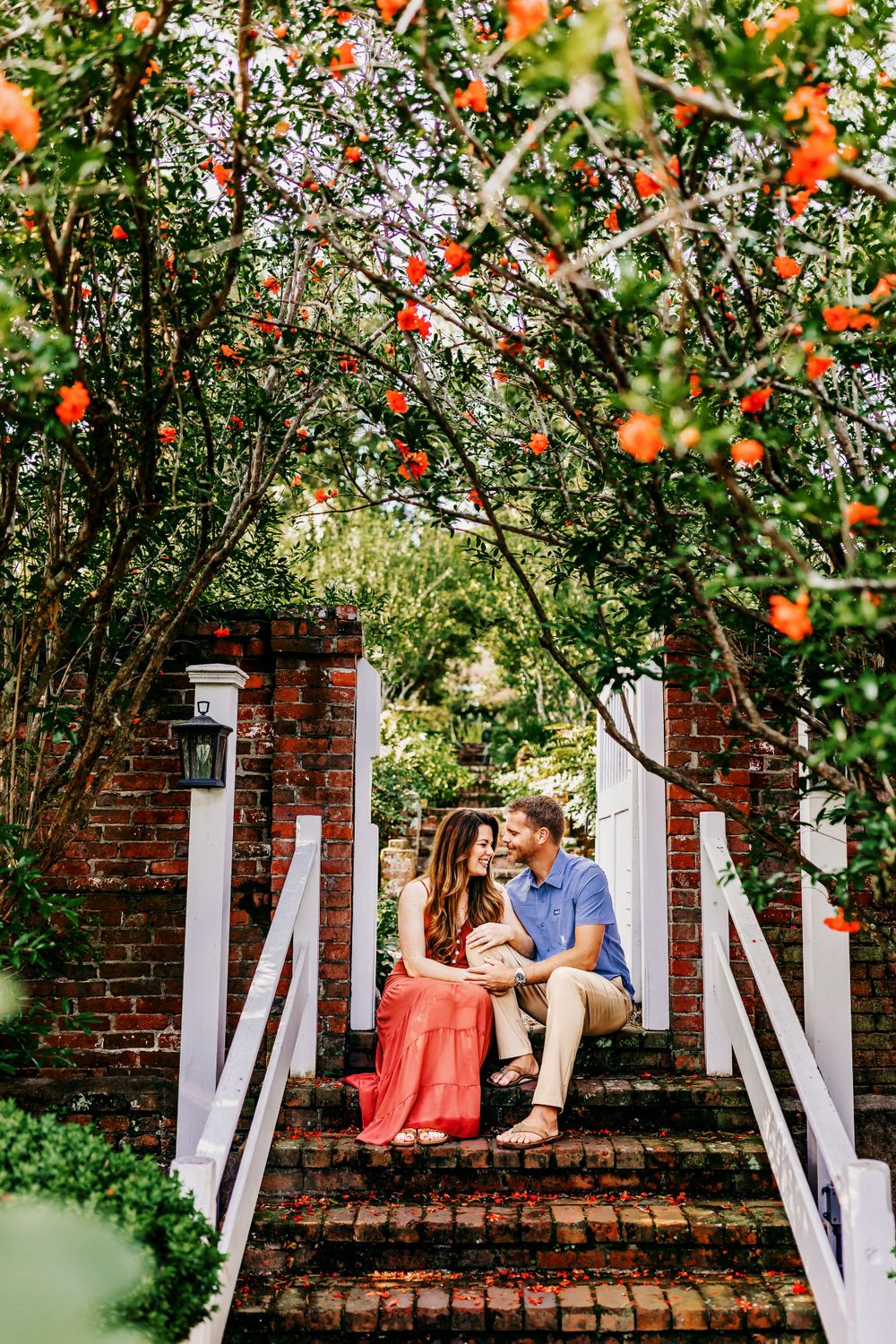 Intimate family portrait under flowering trees on brick steps with white railings.