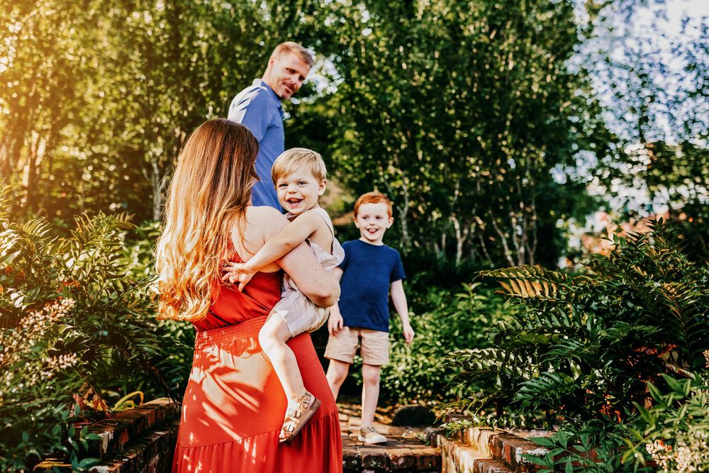 Family portrait in garden with flowering trees and brick staircase.