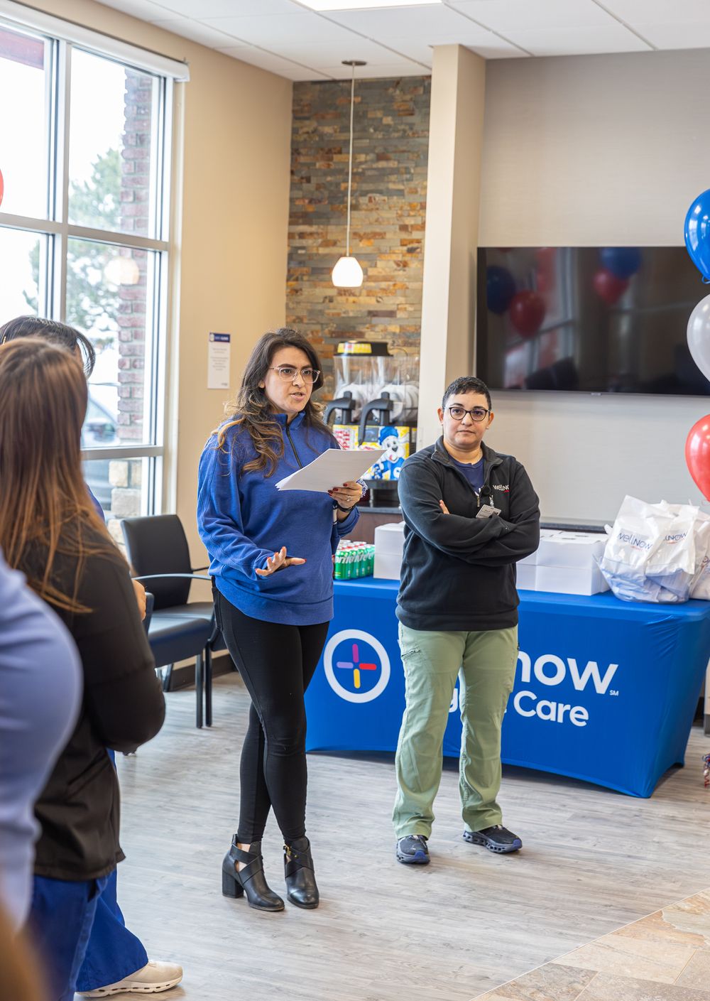 A corporate presentation in an office with blue and white branded banners and balloons.