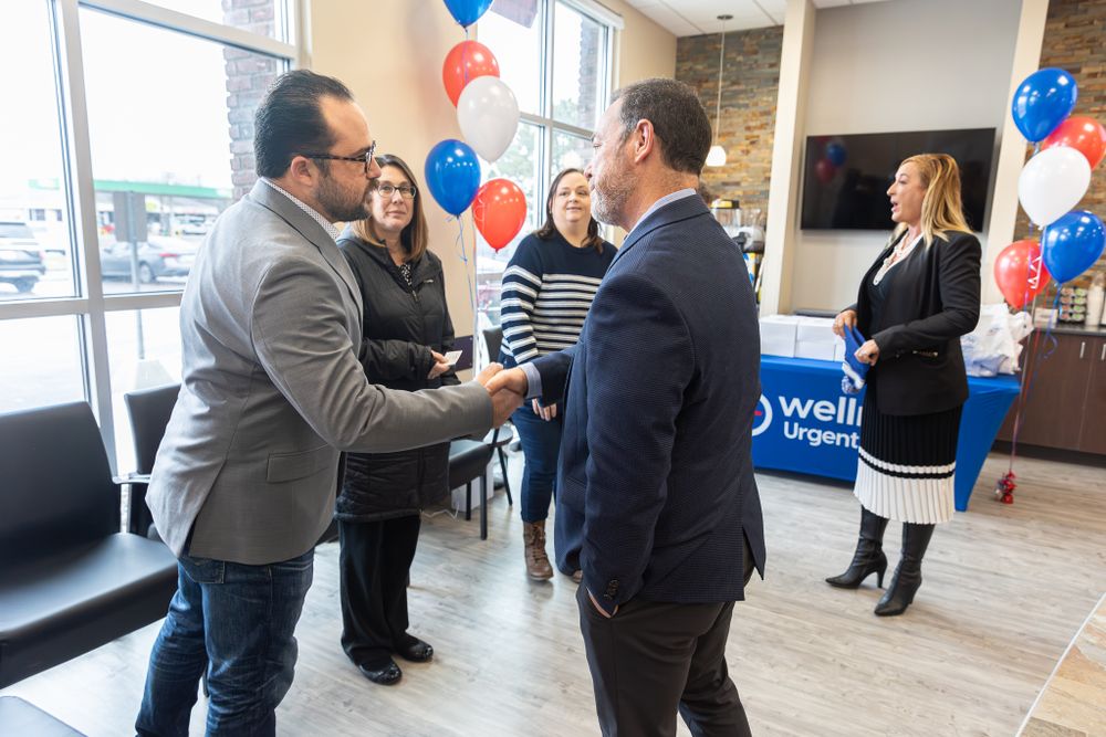 Business professionals having a conversation in an office lobby decorated with red and blue balloons.