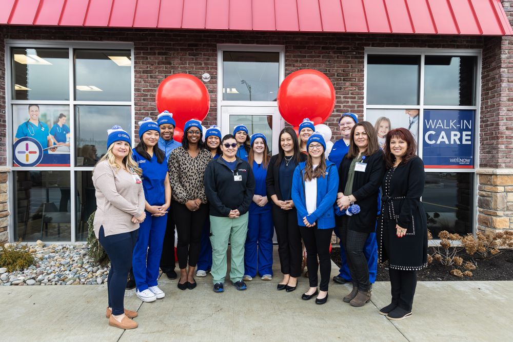 Healthcare team poses for group photo outside medical facility with festive balloon decorations.