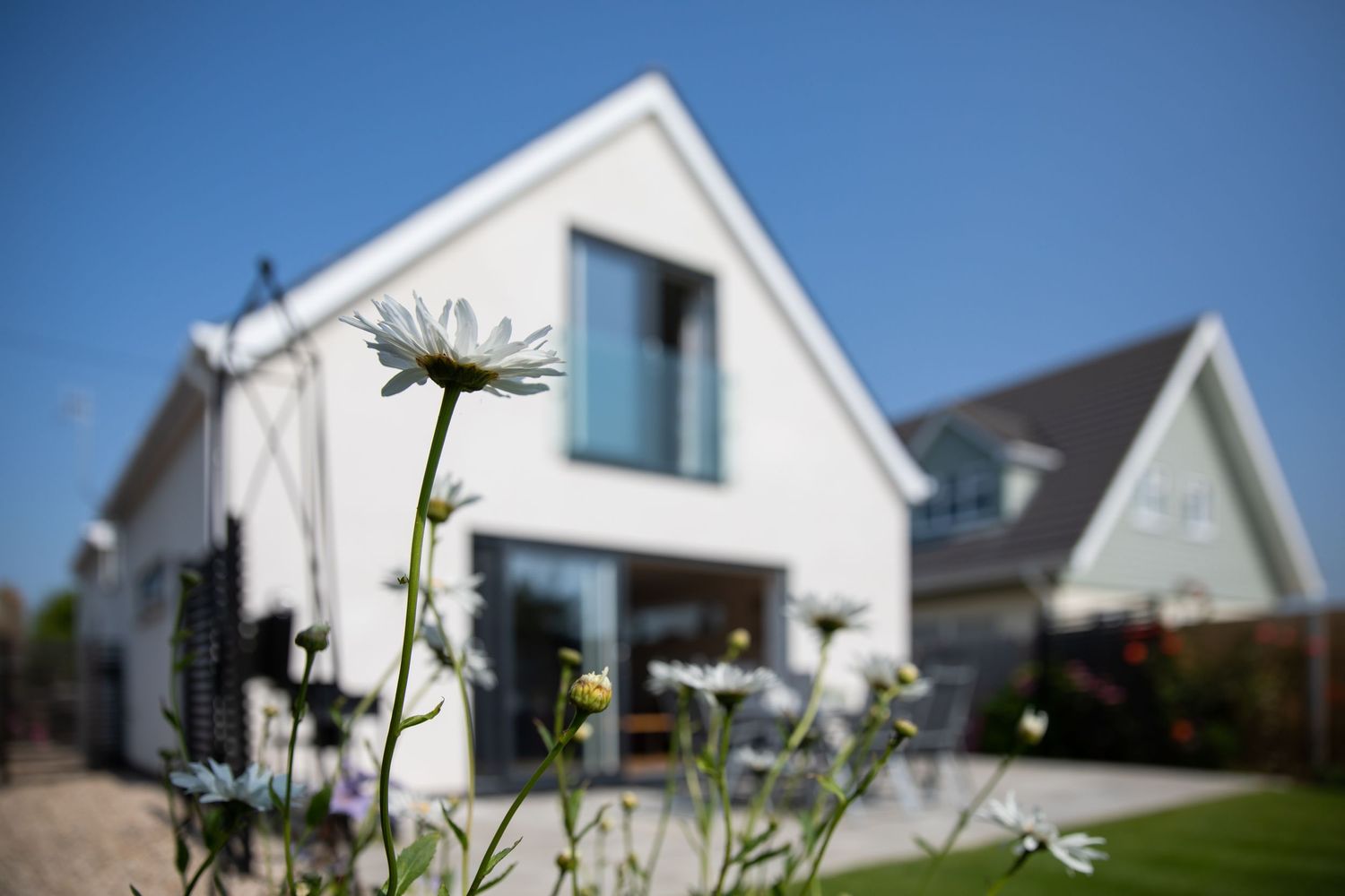 White modern beach house with architectural details seen through blooming flowers.