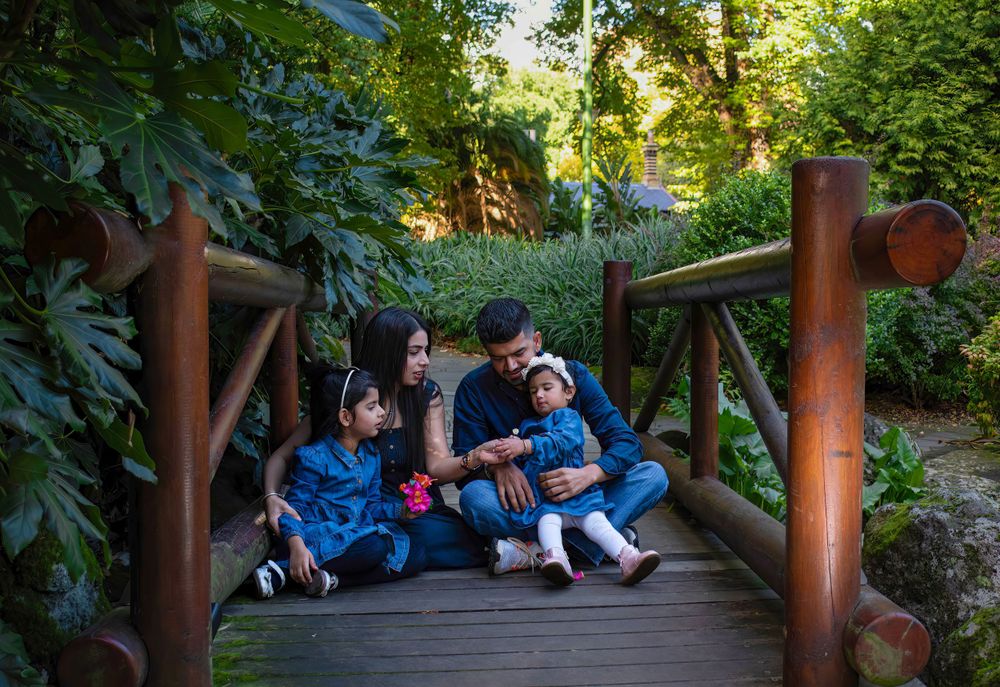 Family sitting together on a wooden bridge walkway surrounded by lush greenery.