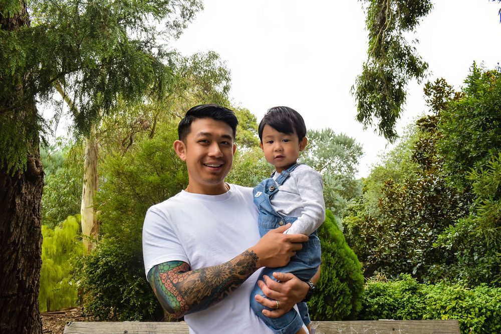 Person in white t-shirt holding child against green forest background.