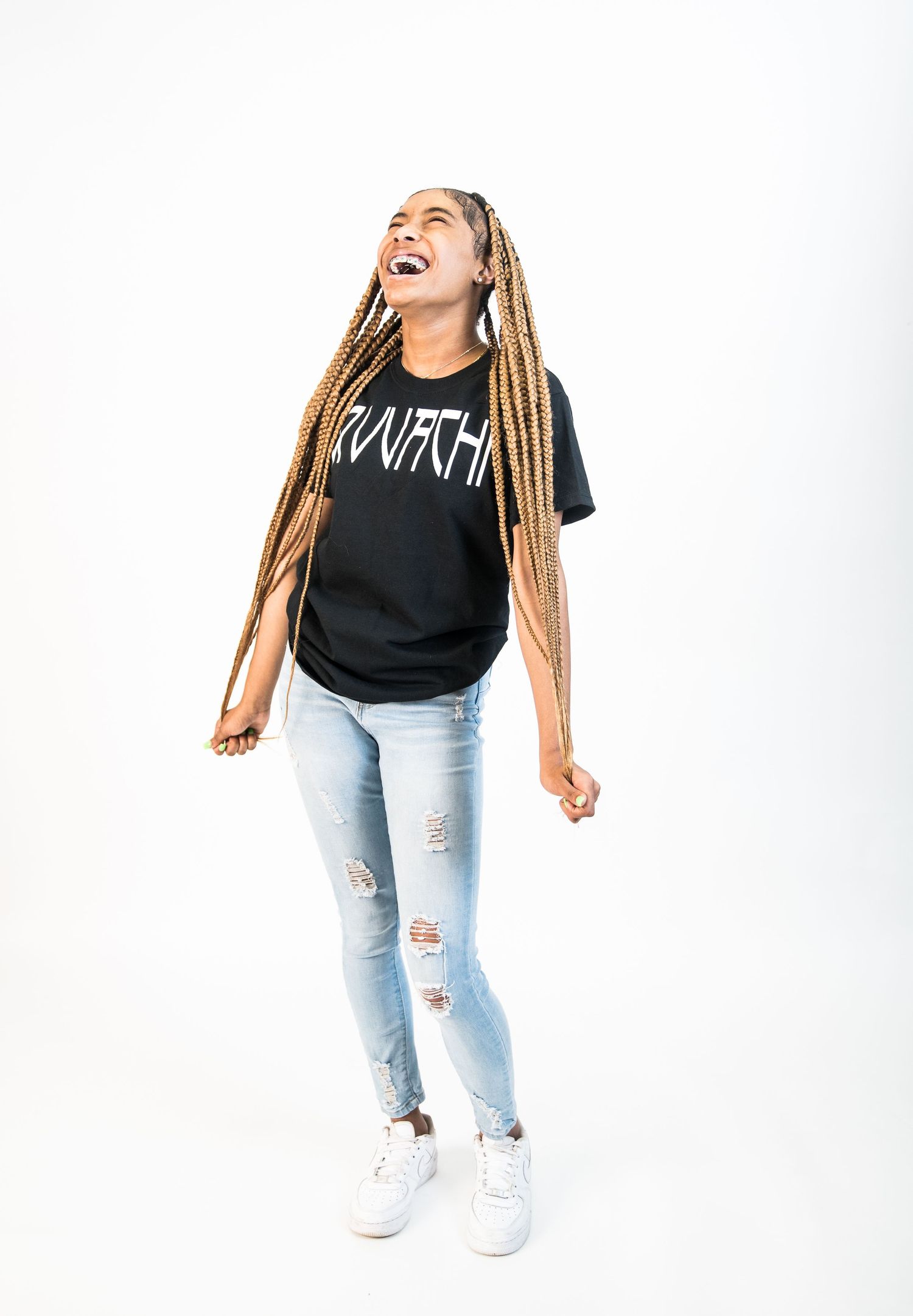 Fashion photoshoot against white backdrop featuring distressed jeans and casual black t-shirt.