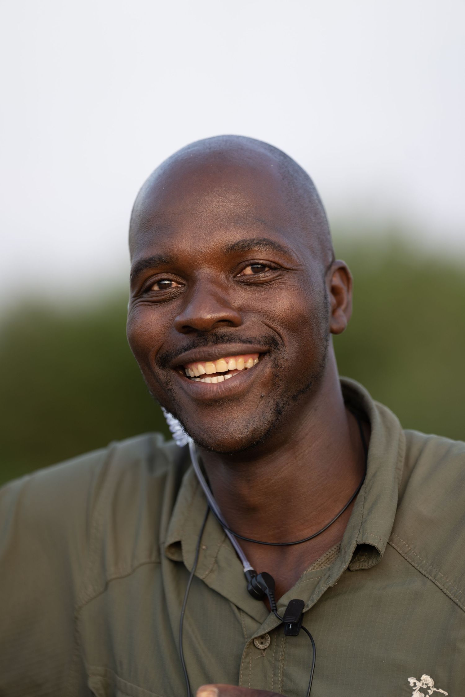 A safari guide in a green shirt shown in various expressions outdoors.