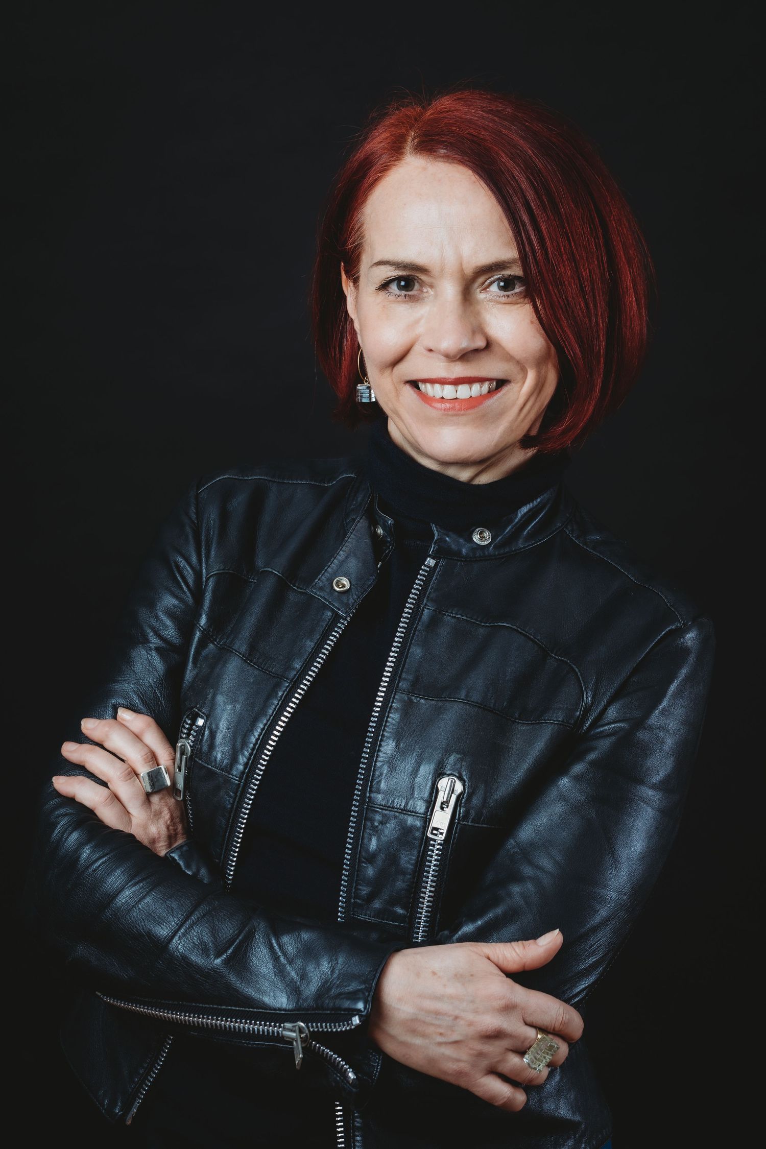 Portrait of person in black leather jacket against dark background, in Stoke Newington studio.