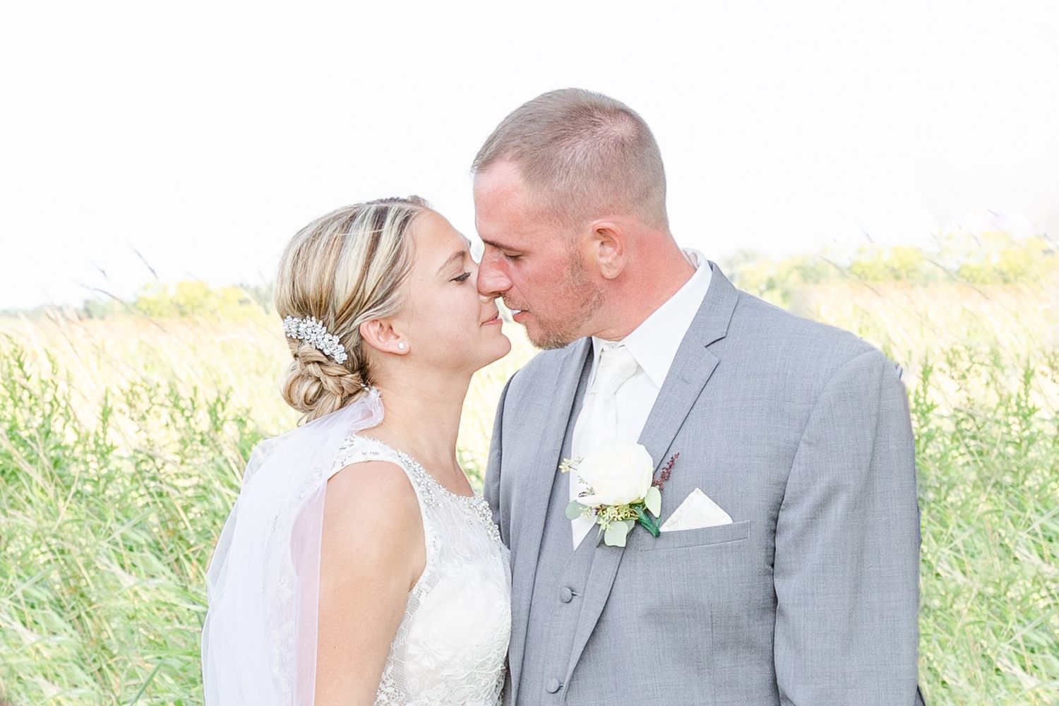 An elegant outdoor summer wedding photo session in a sunlit field.