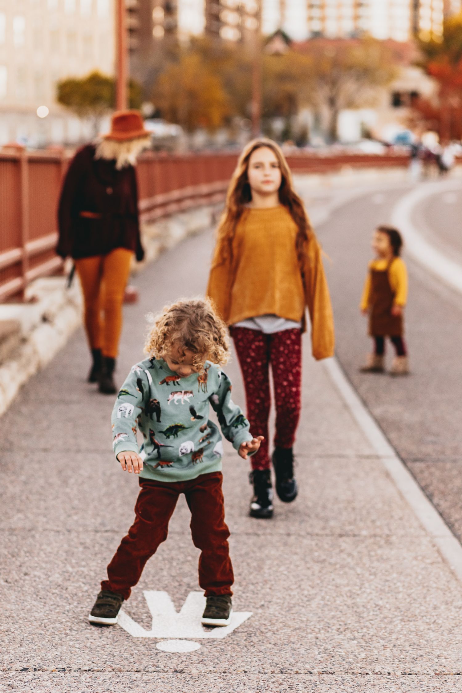 A family dressed in varying shades of yellow, brown, and blue, playfully walk down Minneapolis' Stone Arch Bridge.