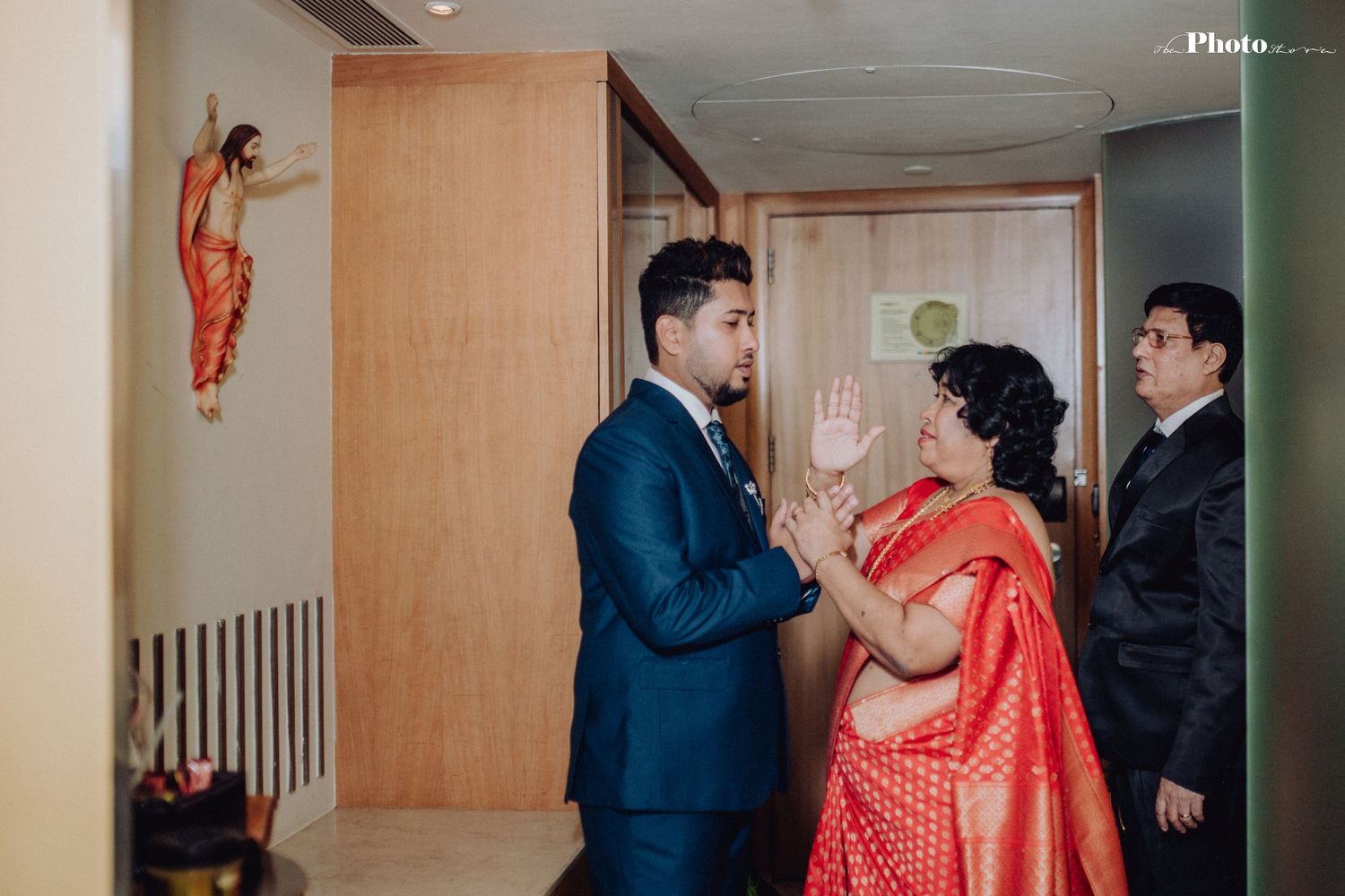 Wedding party members interacting in a warmly lit hotel corridor.