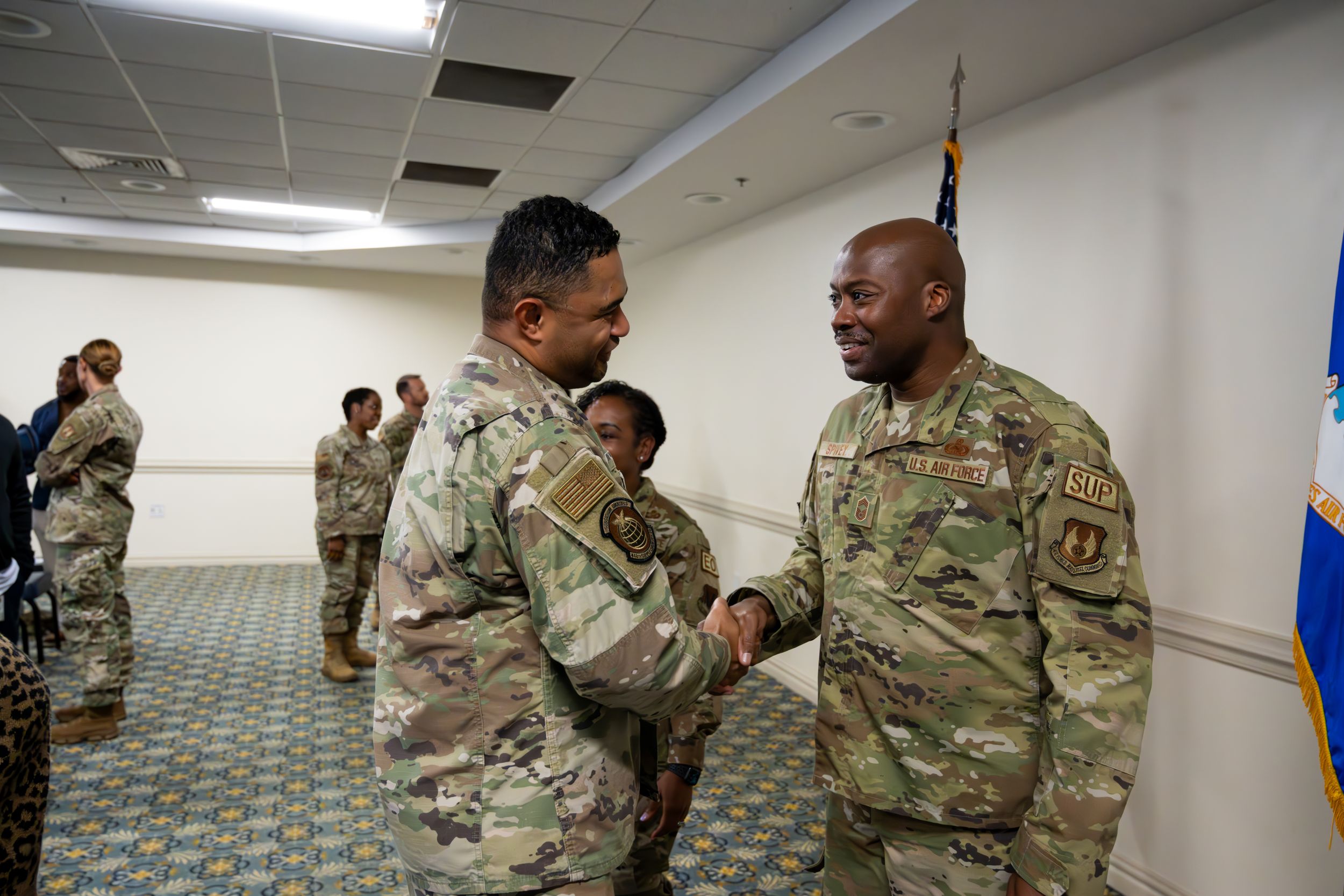 Service members greet and congratulate each other at formal military gathering.