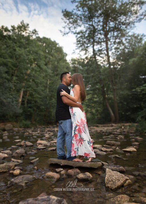 Romantic couple sitting on rocky terrain during outdoor photo session.