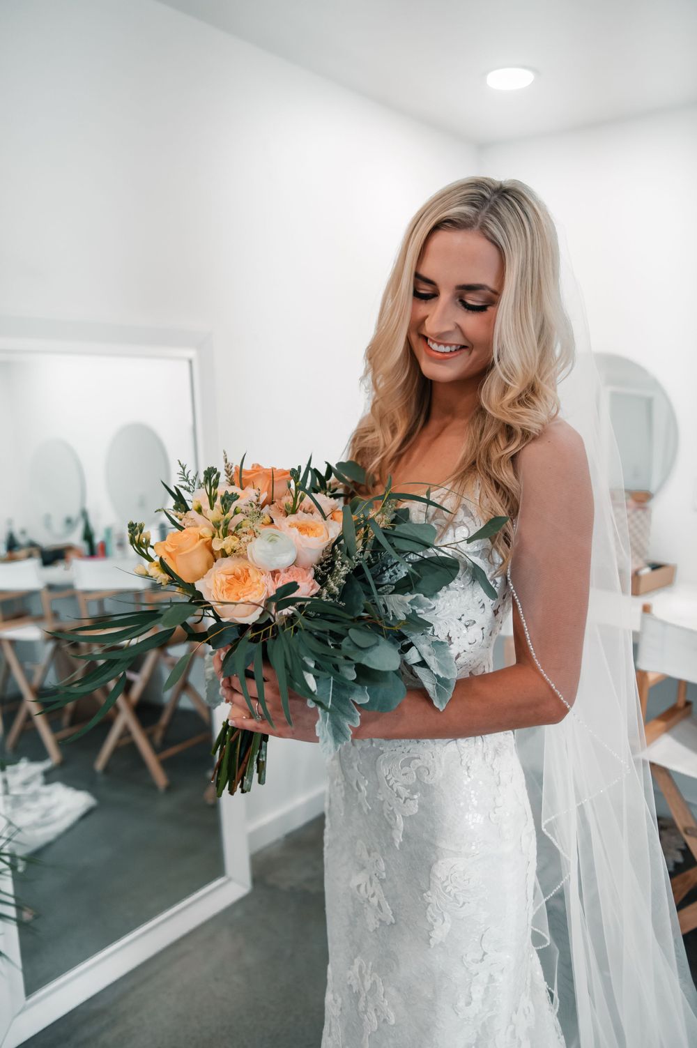 Wedding preparation room with white walls and mirrors decorated with floral arrangements.