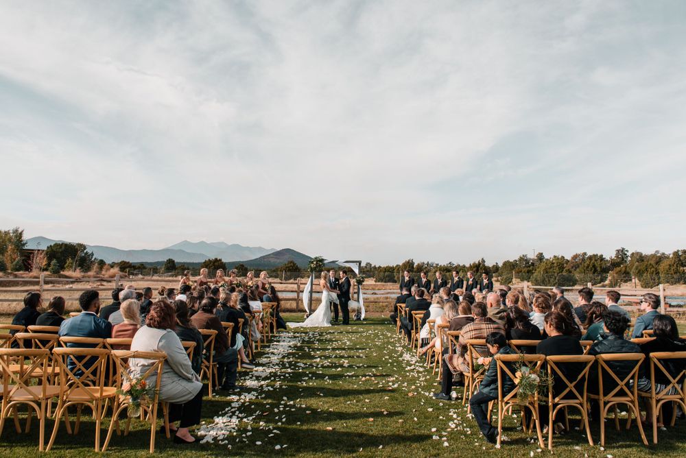 Outdoor wedding ceremony setup with wooden chairs and mountain views in the background.