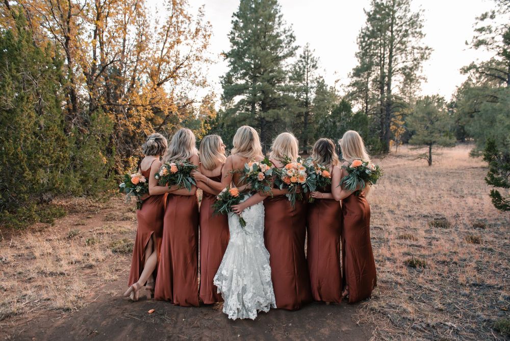 Wedding party in burgundy dresses posing together outdoors during autumn.