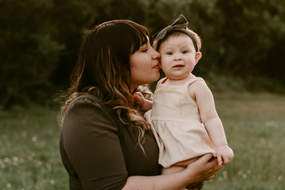 Intimate lifestyle portrait photographed in soft golden light among blooming wildflowers.