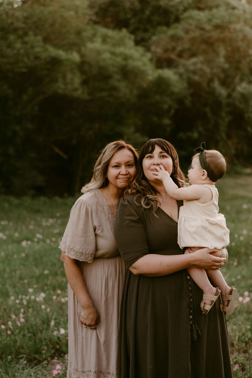 Heartwarming family moment captured in a field during golden hour wearing coordinated neutral dresses.