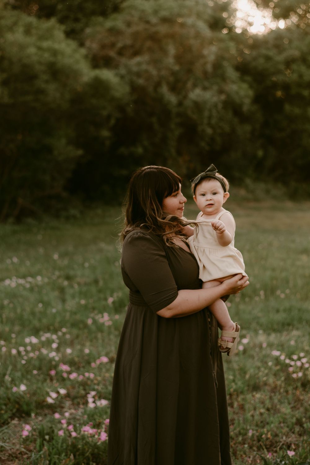 Sweet candid moment captured in a meadow during sunset with matching neutral-toned outfits.