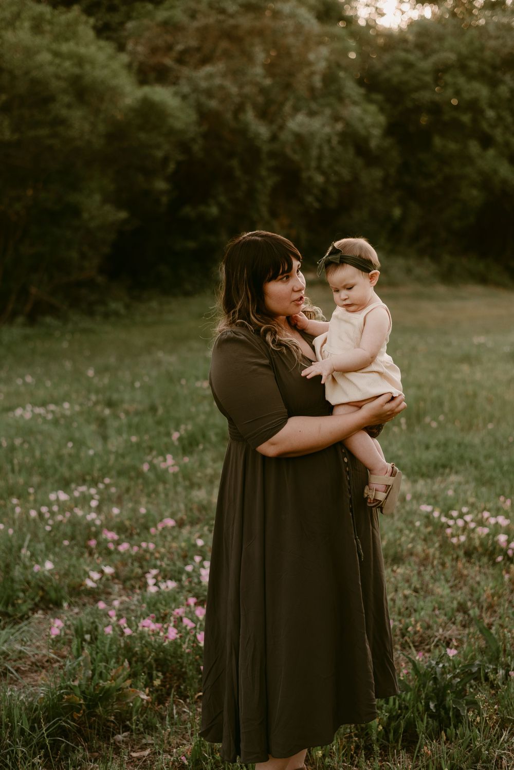 A tender outdoor portrait in a field of wildflowers at golden hour featuring warm earth-toned dresses.