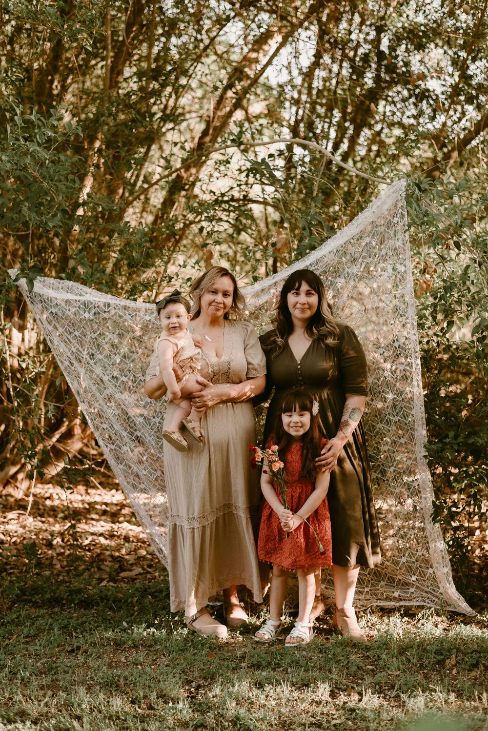 A group photo with decorative lace backdrop in a wooded outdoor setting.