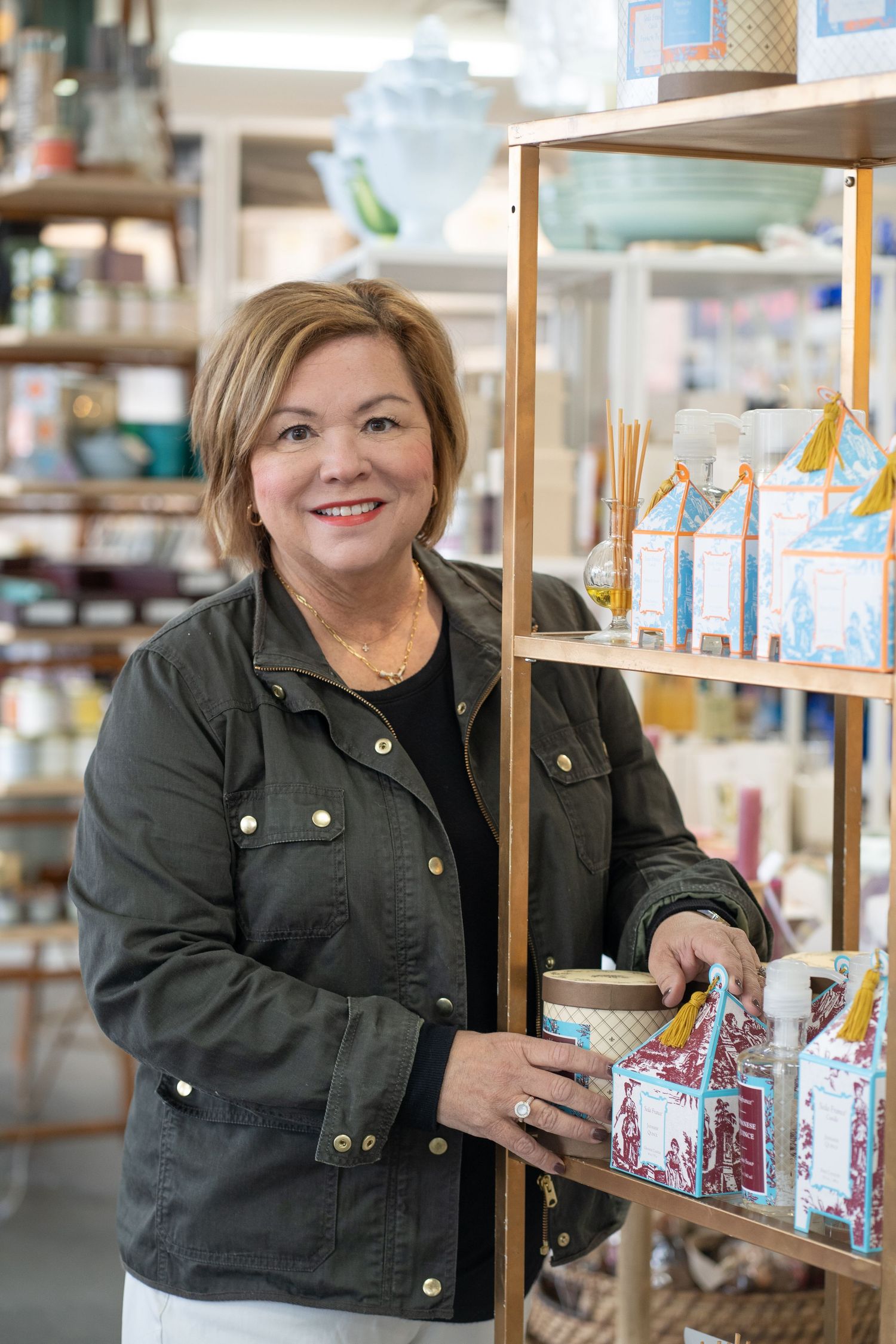 Retail employee in dark jacket stands by display shelf with products in store setting.
