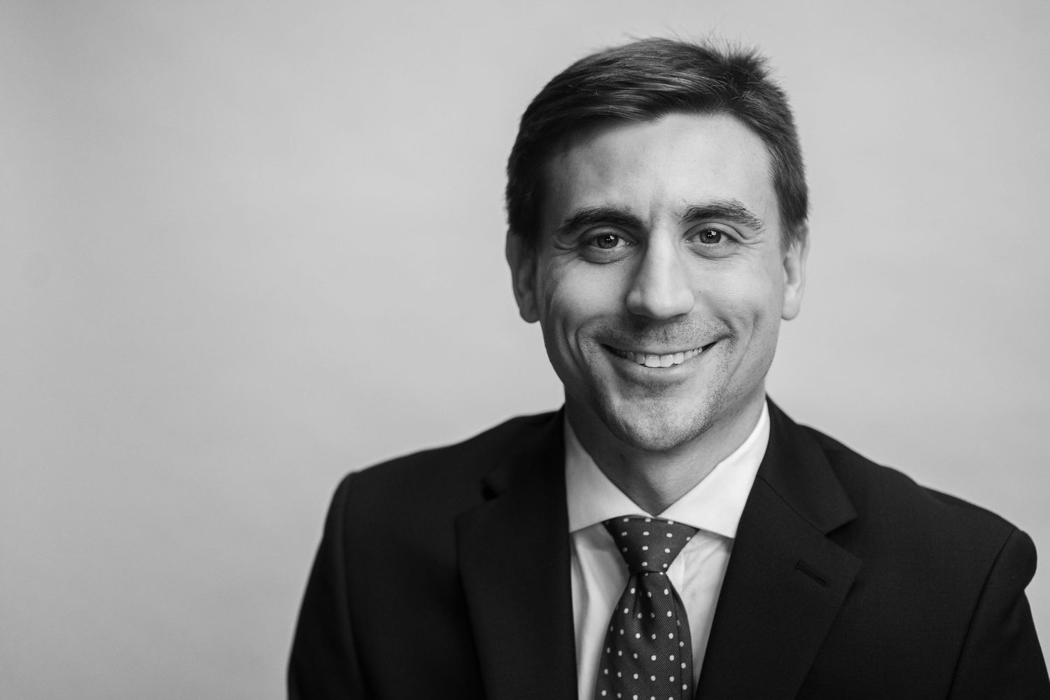 Black and white professional headshot of businessman in suit and tie.