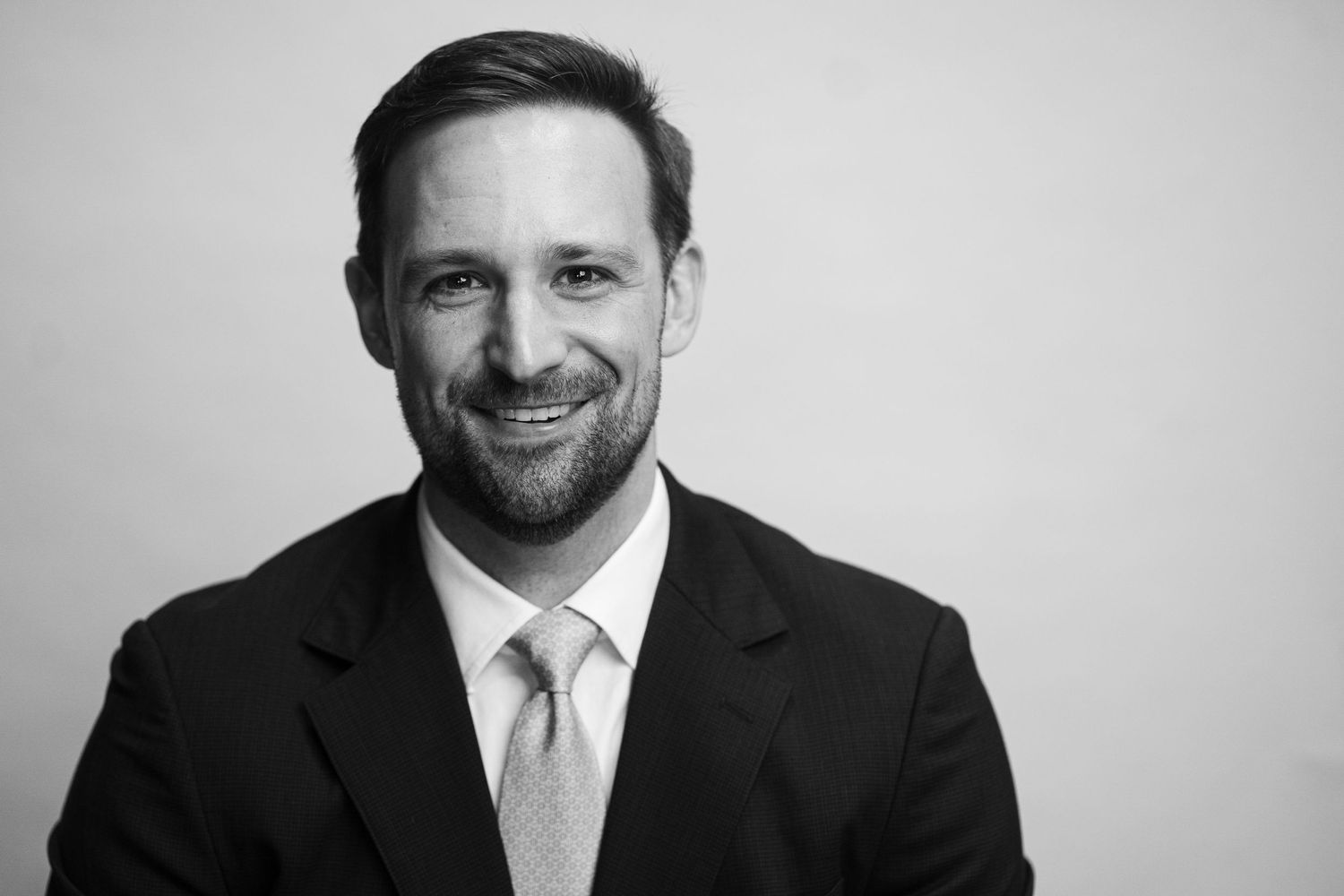 Black and white professional headshot of businessman wearing light tie.