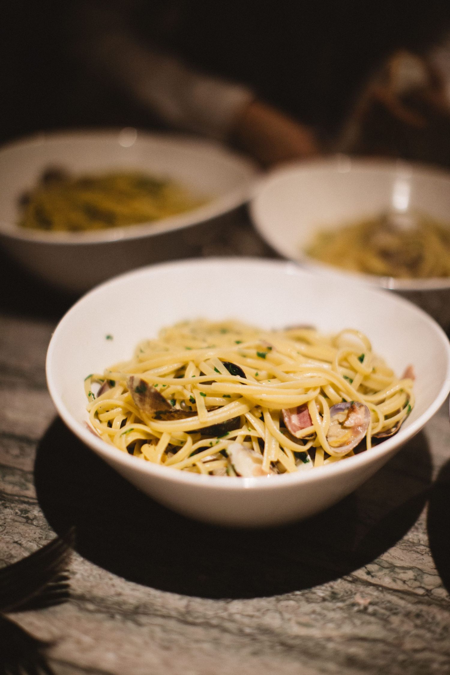 Bowl of freshly cooked pasta with sauce served on a rustic wooden table.