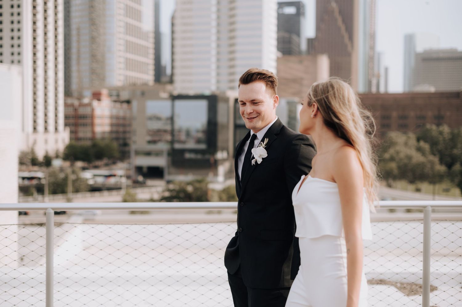 Modern wedding couple poses against urban cityscape backdrop.