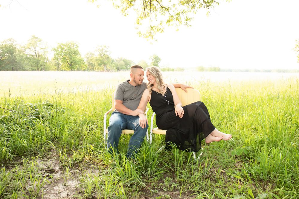 Two people share a tender moment while sitting in a sun-drenched field.