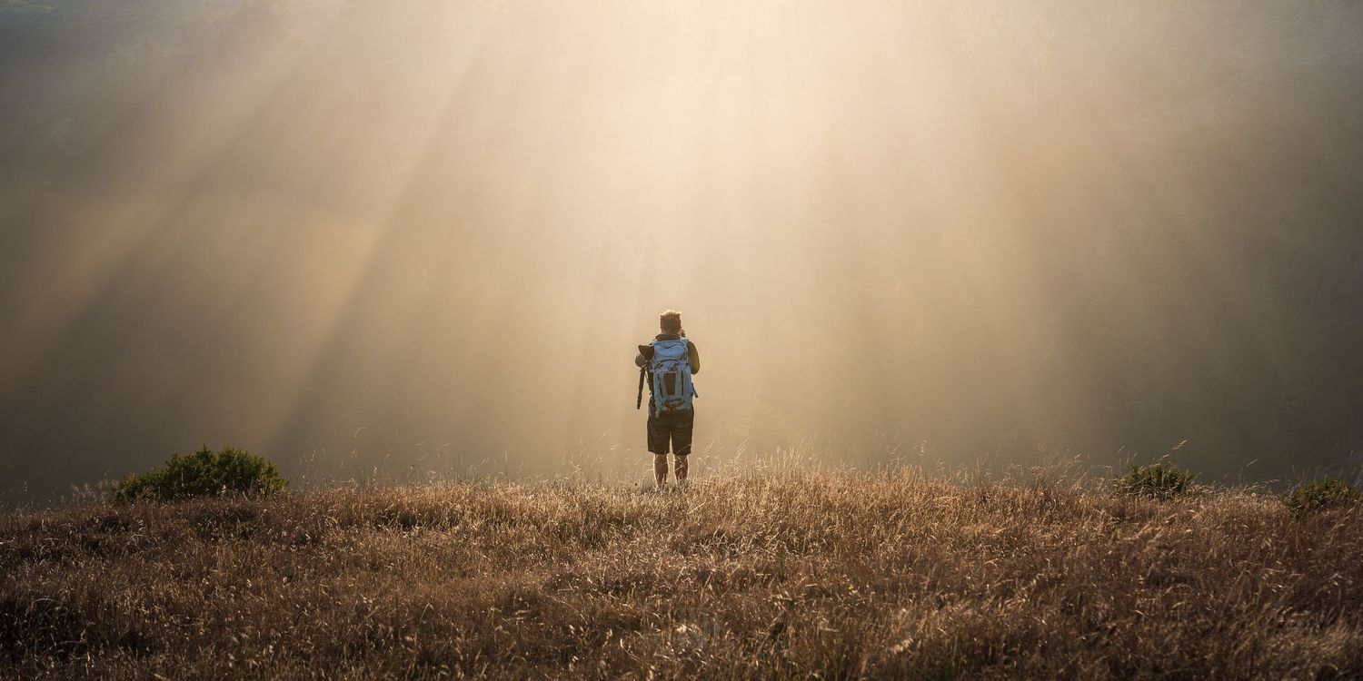 Silhouette of Jeff in golden sunbeams standing on a misty mountain ridge at sunrise. Mt. Tamalpais, California