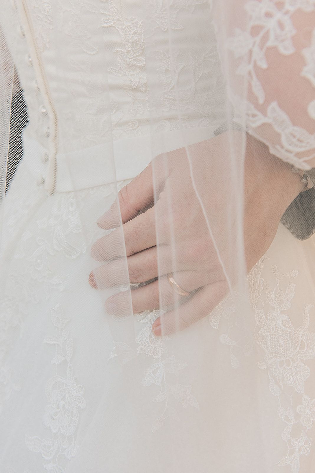 Close-up detail shot of delicate lace and tulle on a white wedding dress.