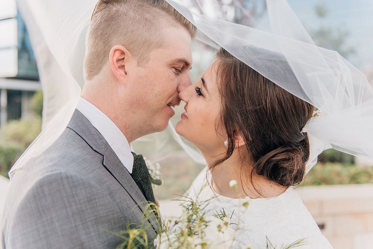 Intimate wedding portrait showing a romantic moment under a sheer white veil.