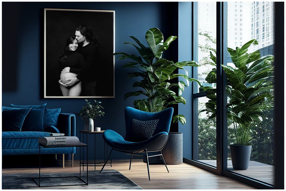 Black and white maternity couple portrait displayed as wall art in modern teal living room with velvet sofa and floor-to-ceiling windows