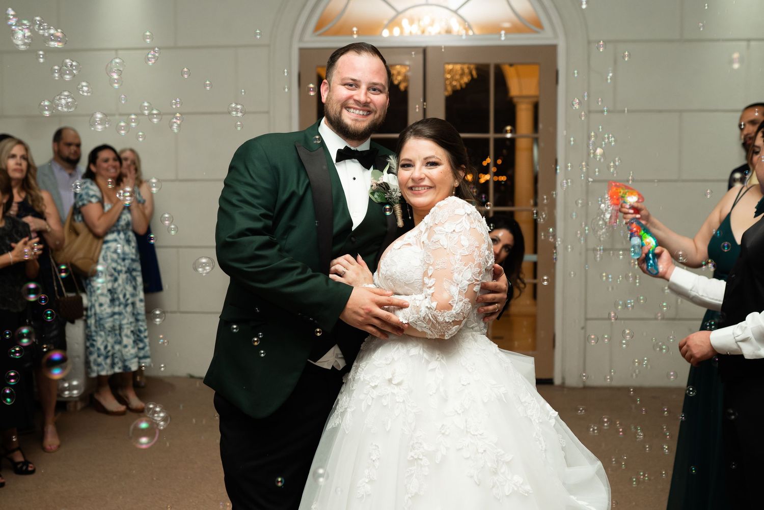 Newlyweds share their first dance surrounded by floating bubbles at an indoor wedding reception.