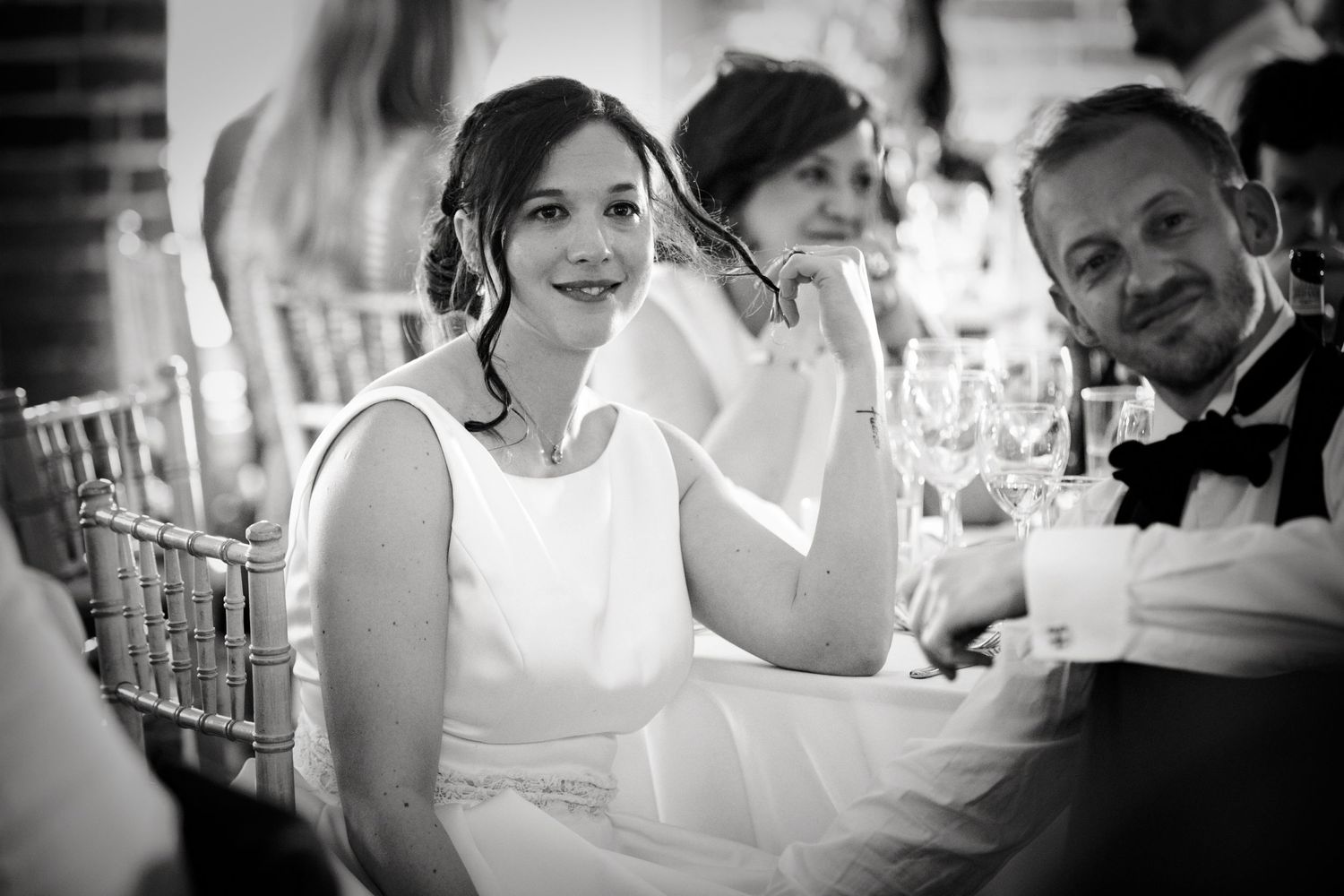 Black and white candid shots capturing genuine laughter during wedding reception.