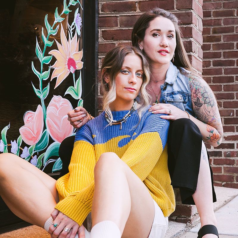 Young female entrepreneurs sitting in front of their new store