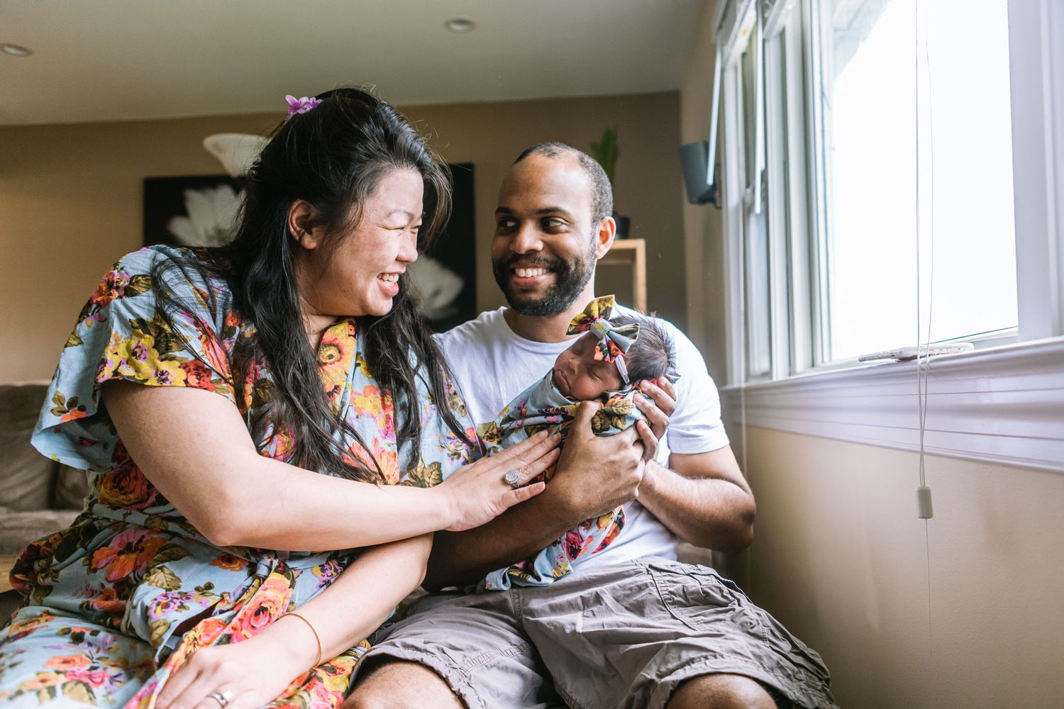 new mom and dad with lovingly glance while holding newborn baby photo taken by heart and root photography
