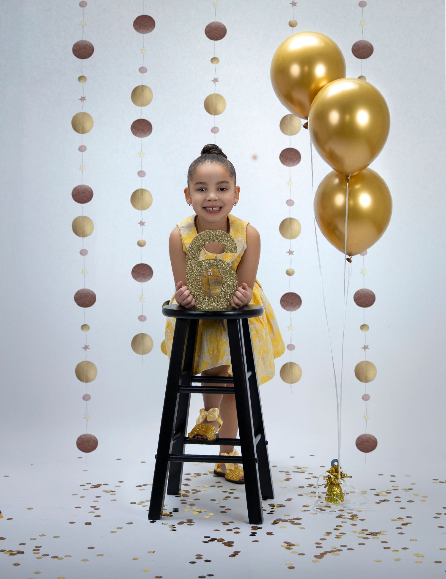 Birthday photoshoot setup with gold balloons and polka dot backdrop.