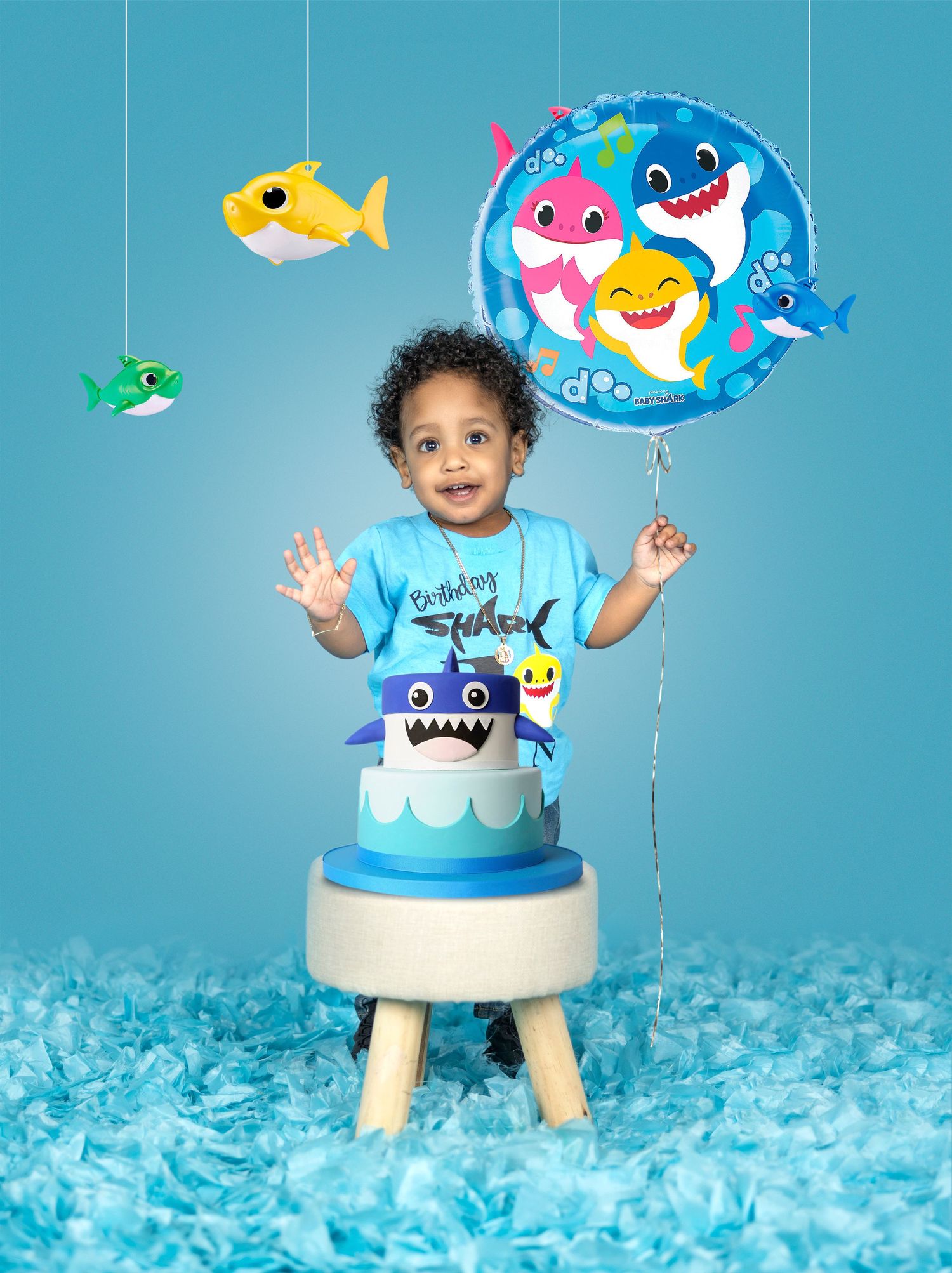 Baby shark themed birthday setup with blue background and hanging fish decorations.