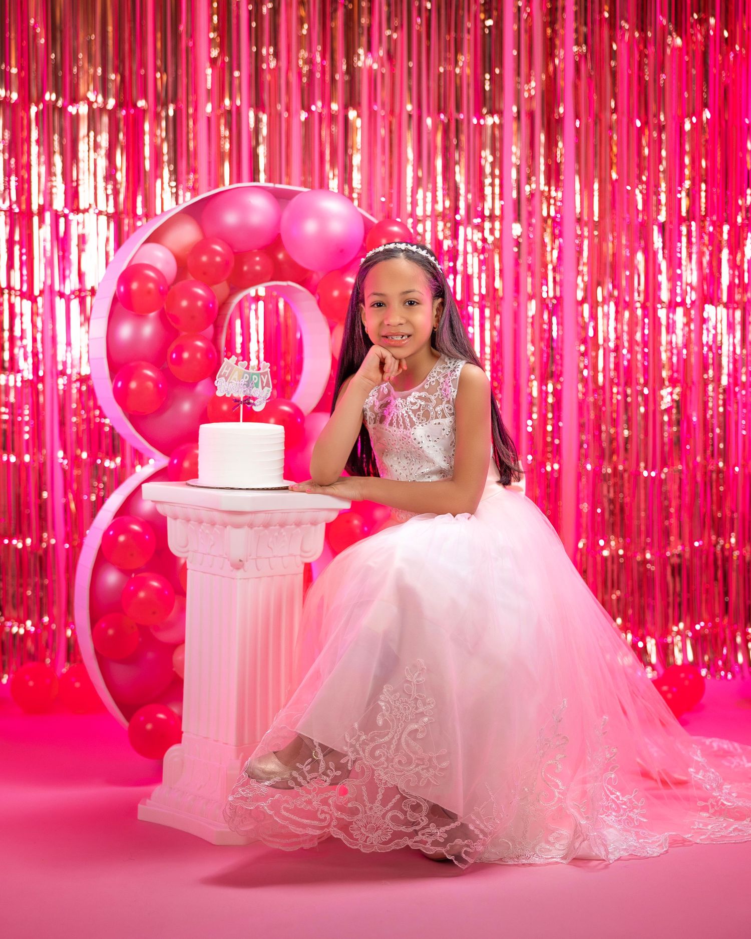 Pink sparkly birthday photoshoot setup with balloon number and glitter curtain backdrop.