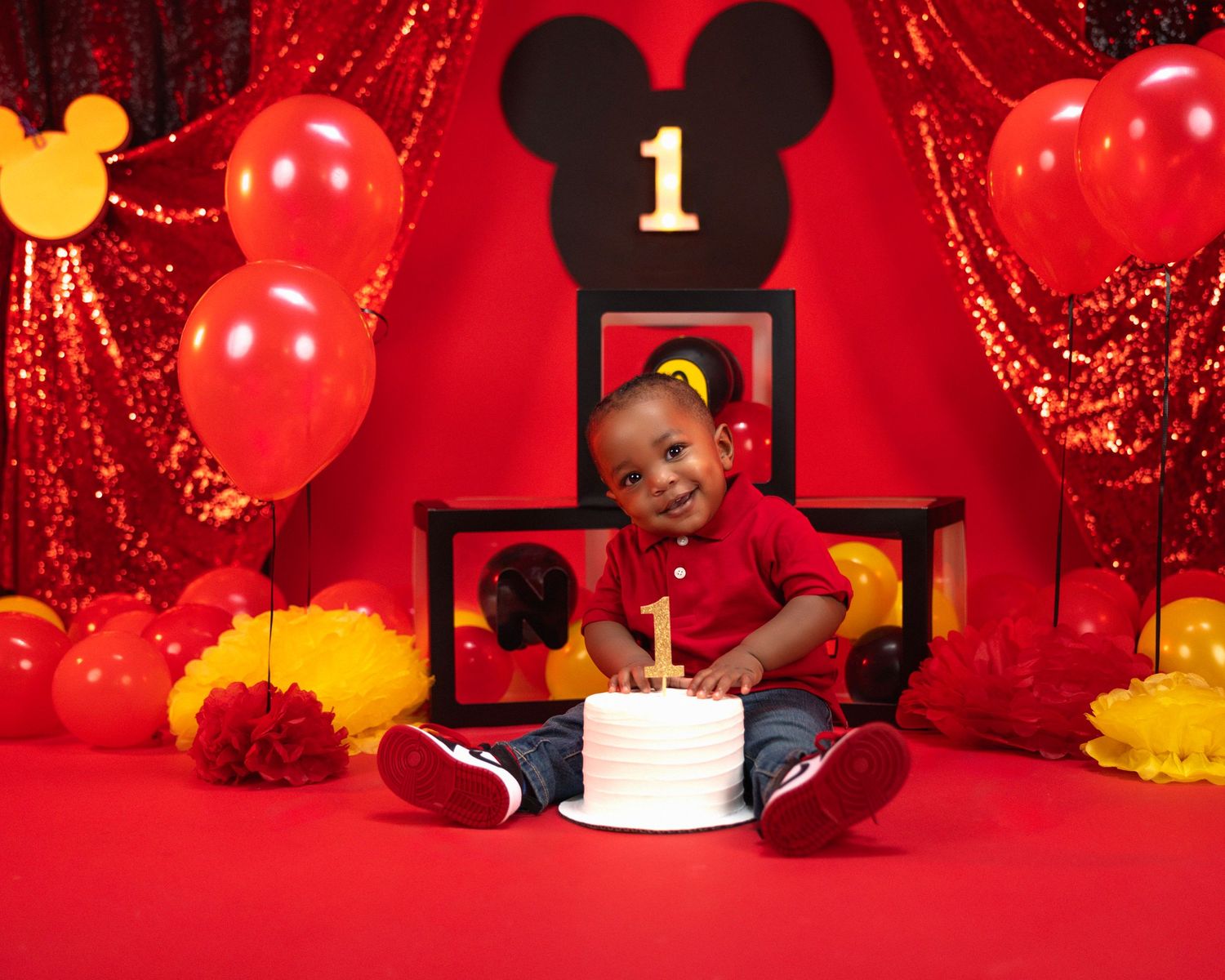 First birthday celebration with Mickey Mouse theme and red balloon decorations.