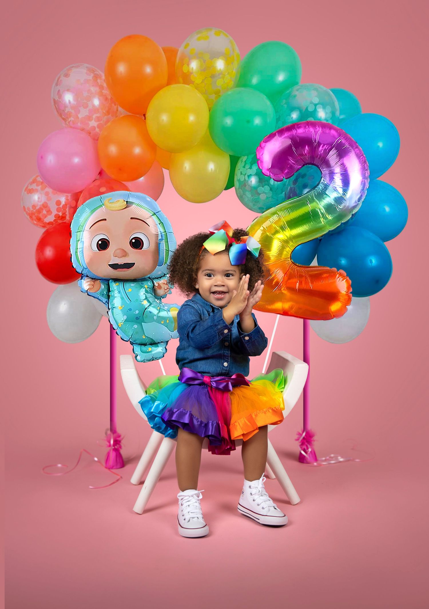 Colorful birthday party setup with rainbow balloons and number 2 balloon against pink backdrop.
