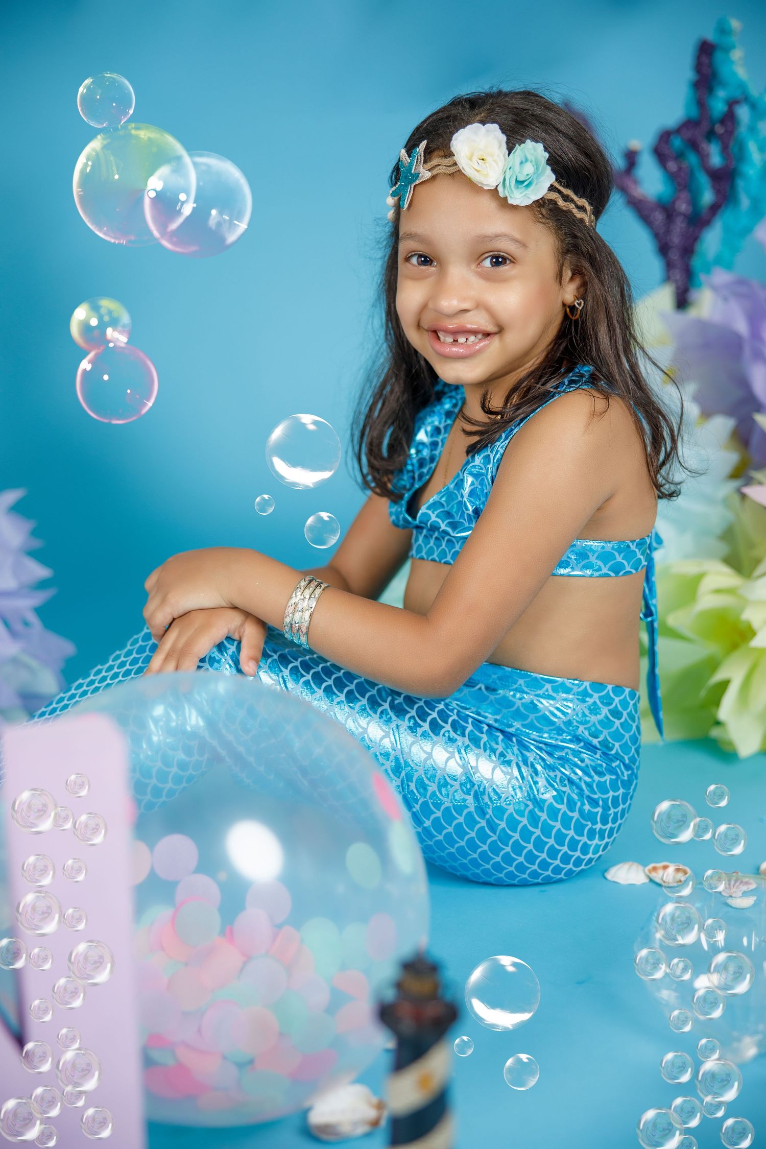 Magical mermaid themed photoshoot with bubbles and turquoise backdrop.