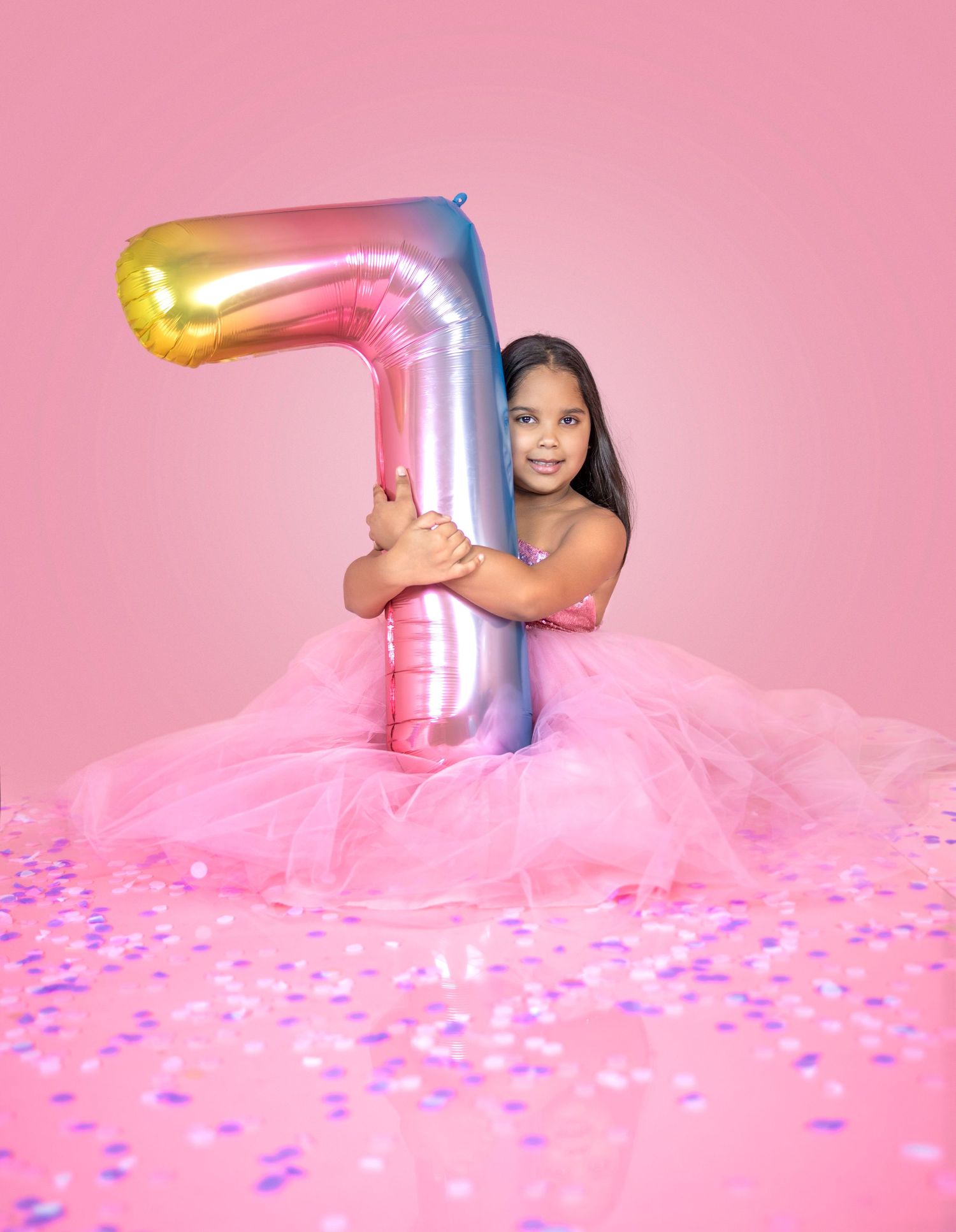 Pink birthday photoshoot featuring large silver number 7 balloon and tulle dress.