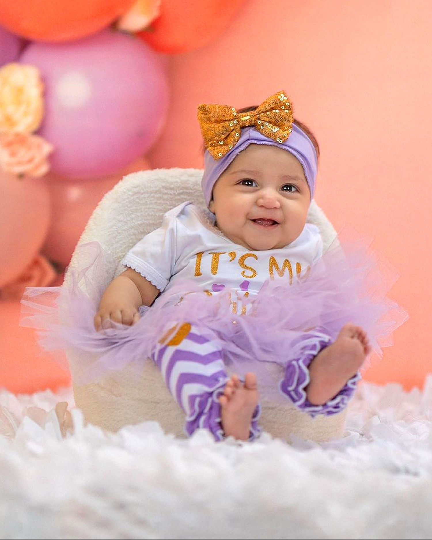 Purple and gold themed first birthday photo with tulle decorations.