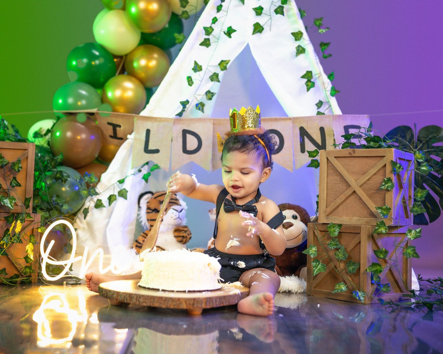 Wild One themed first birthday cake smash with green and gold decorations.