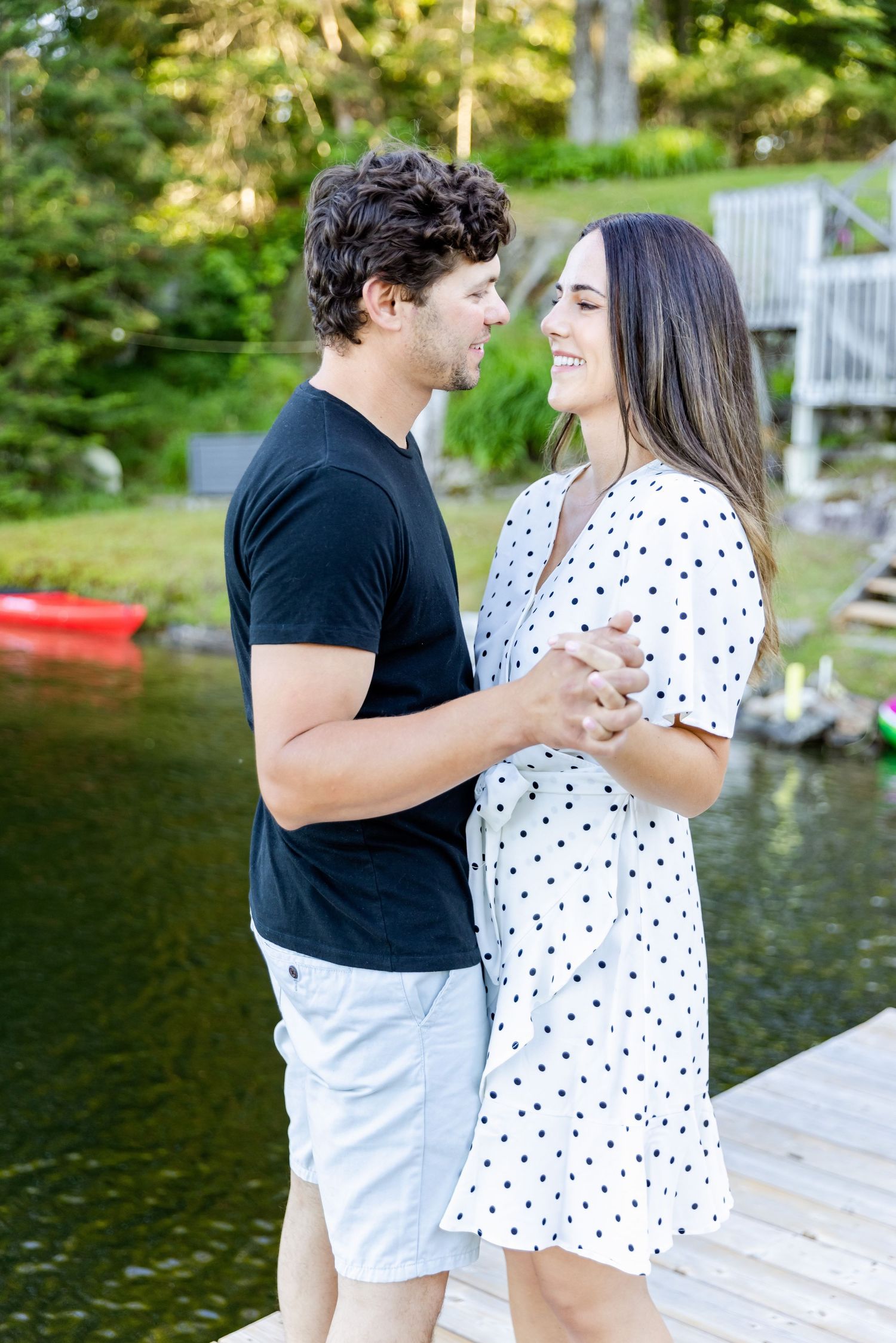 A couple shares a romantic moment on a dock with a red kayak visible in the background.