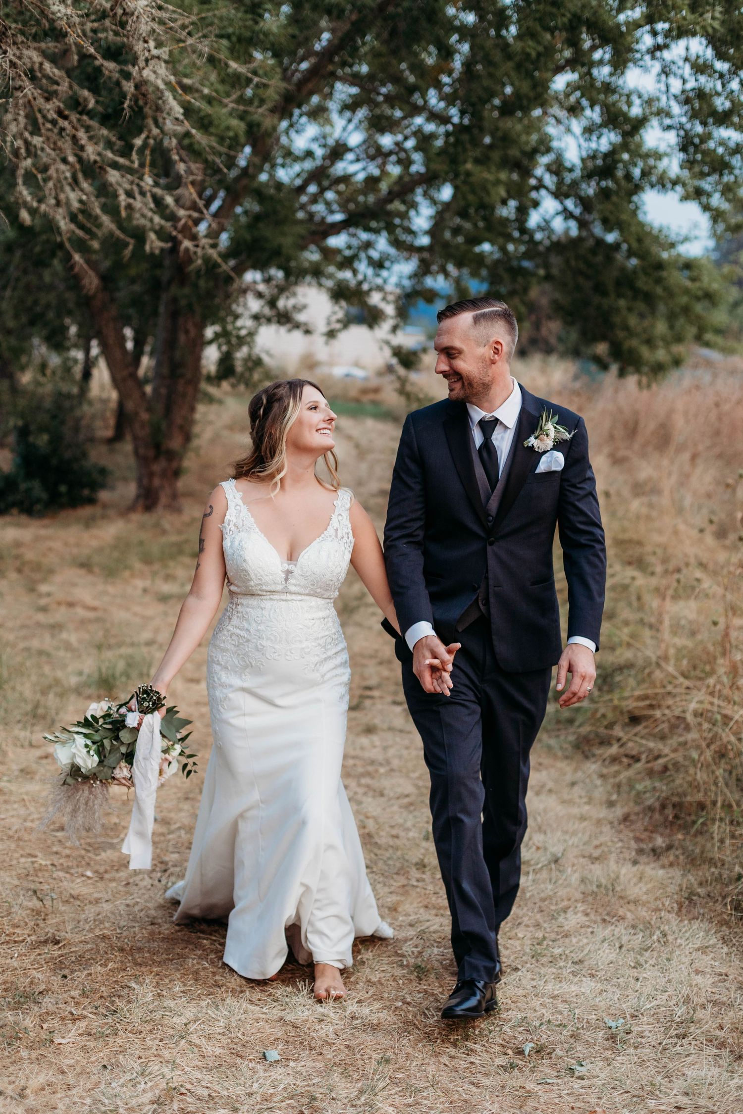 Bride and groom walking together on a natural path through autumn foliage.